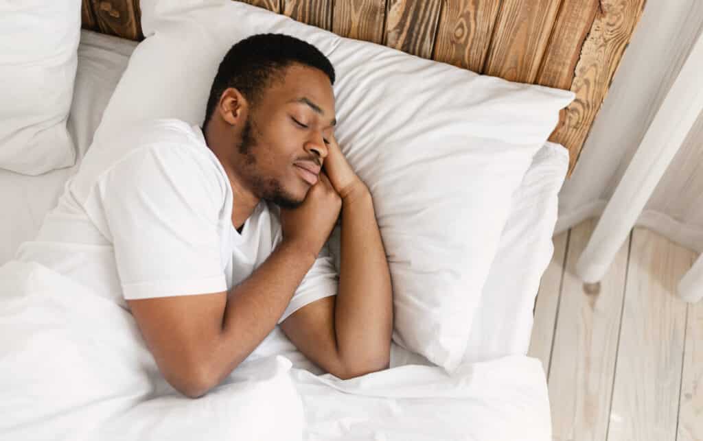 A man sleeping peacefully resting with eyes closed lying in a comfortable bed in his bedroom at home.