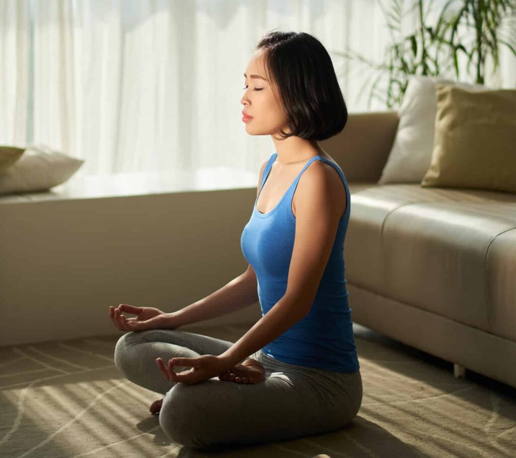 A woman meditating at home in the morning.