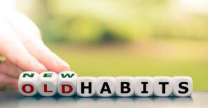 Hand turns dice and changes the expression "old habits" to "new habits."