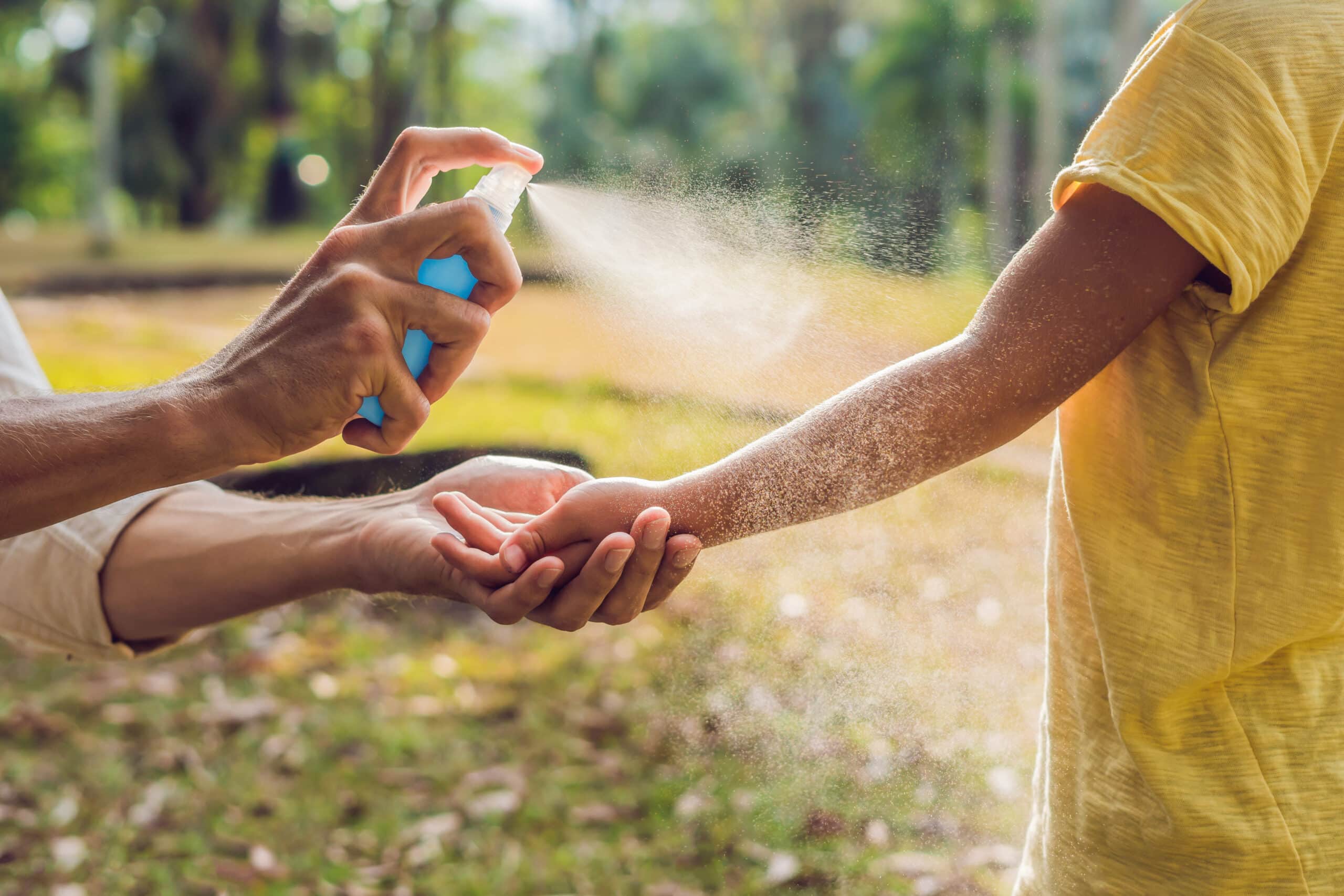 dad and son use mosquito spray.Spraying insect repellent on skin outdoor.