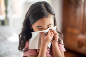 A child sneezing or blowing their nose into a tissue.