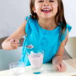A child smiling while eating yogurt.